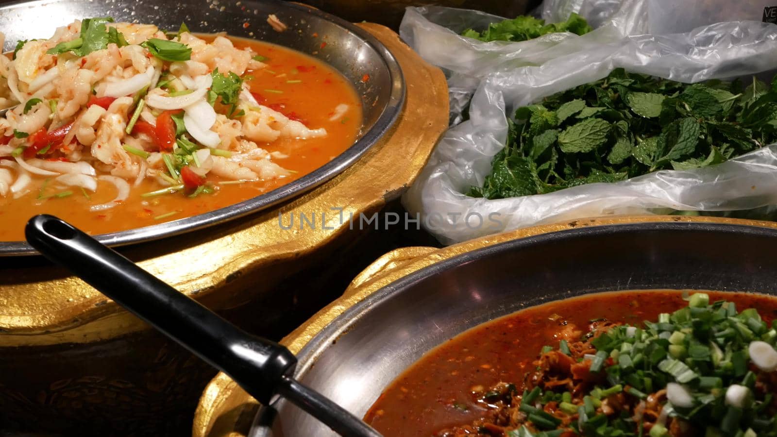 Bowls with various Asian dishes on stall. Bowls of assorted traditional Thai dishes placed on stall of street diner in evening. Oriental night market food court. by DogoraSun