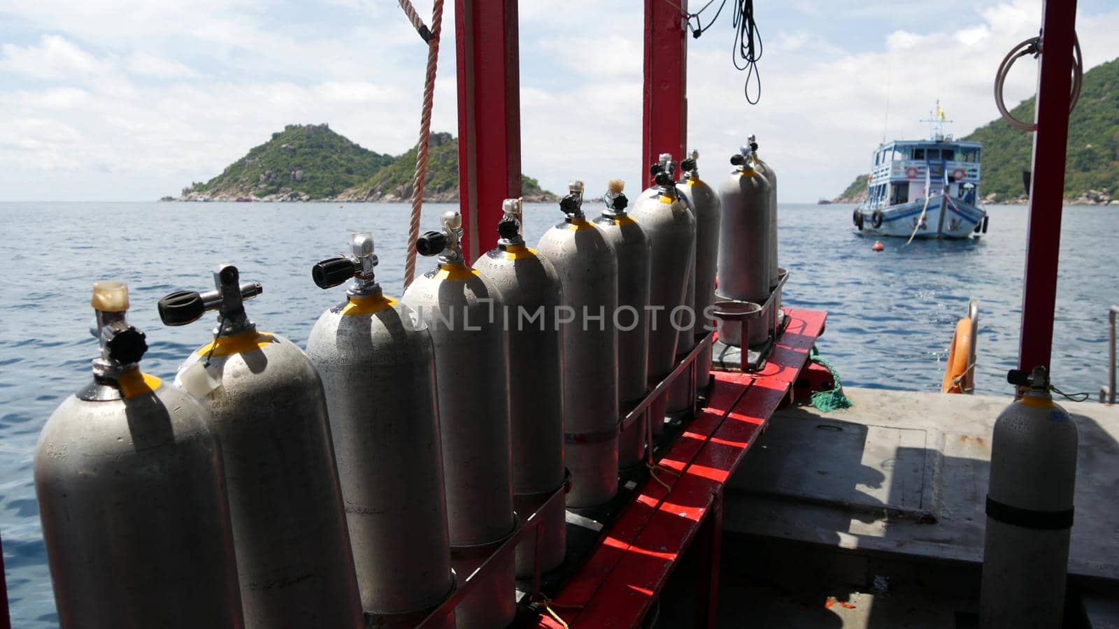 Row of oxygen tanks and diving equipment placed on modern boat in rippling ocean near Koh Tao resort, Thailand. Concept of tourist sports extreme entertainment, adventure and new experience