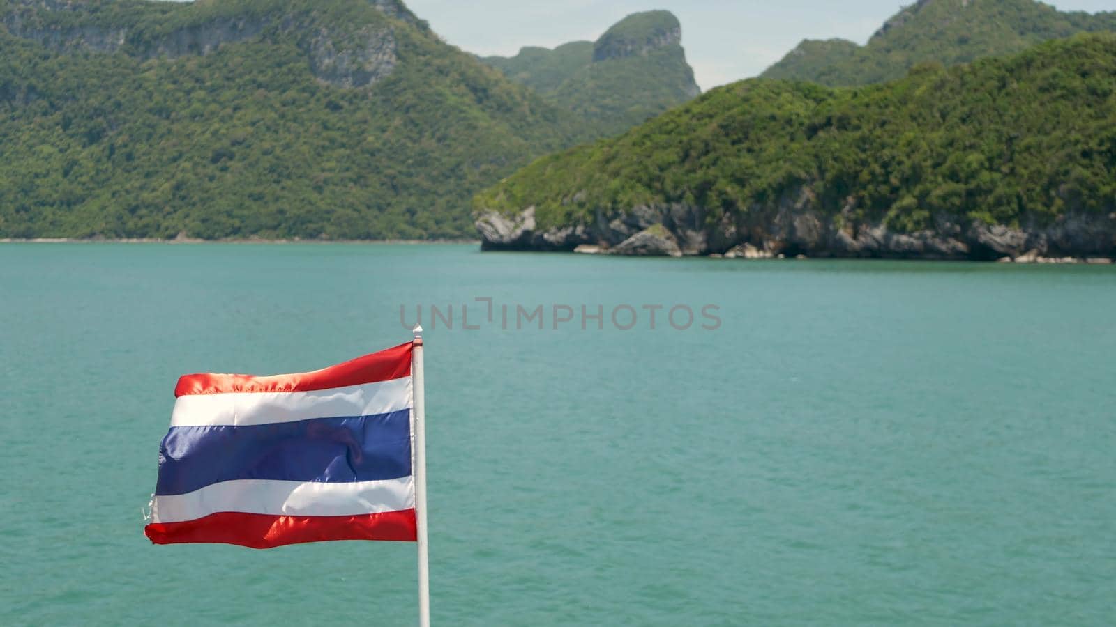 Group of Islands in ocean at Ang Thong National Marine Park. Archipelago in the Gulf of Thailand. Idyllic turquoise sea natural background with copy space. Waving flag as national symbol on the boat. by DogoraSun
