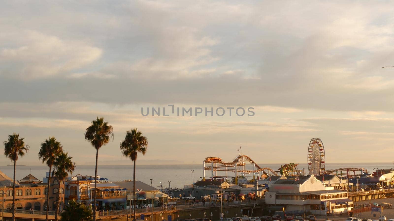 Classic ferris wheel, amusement park on pier in Santa Monica pacific ocean beach resort. Summertime California aesthetic, iconic view, symbol of Los Angeles, CA USA. Sunset golden sky and attractions.