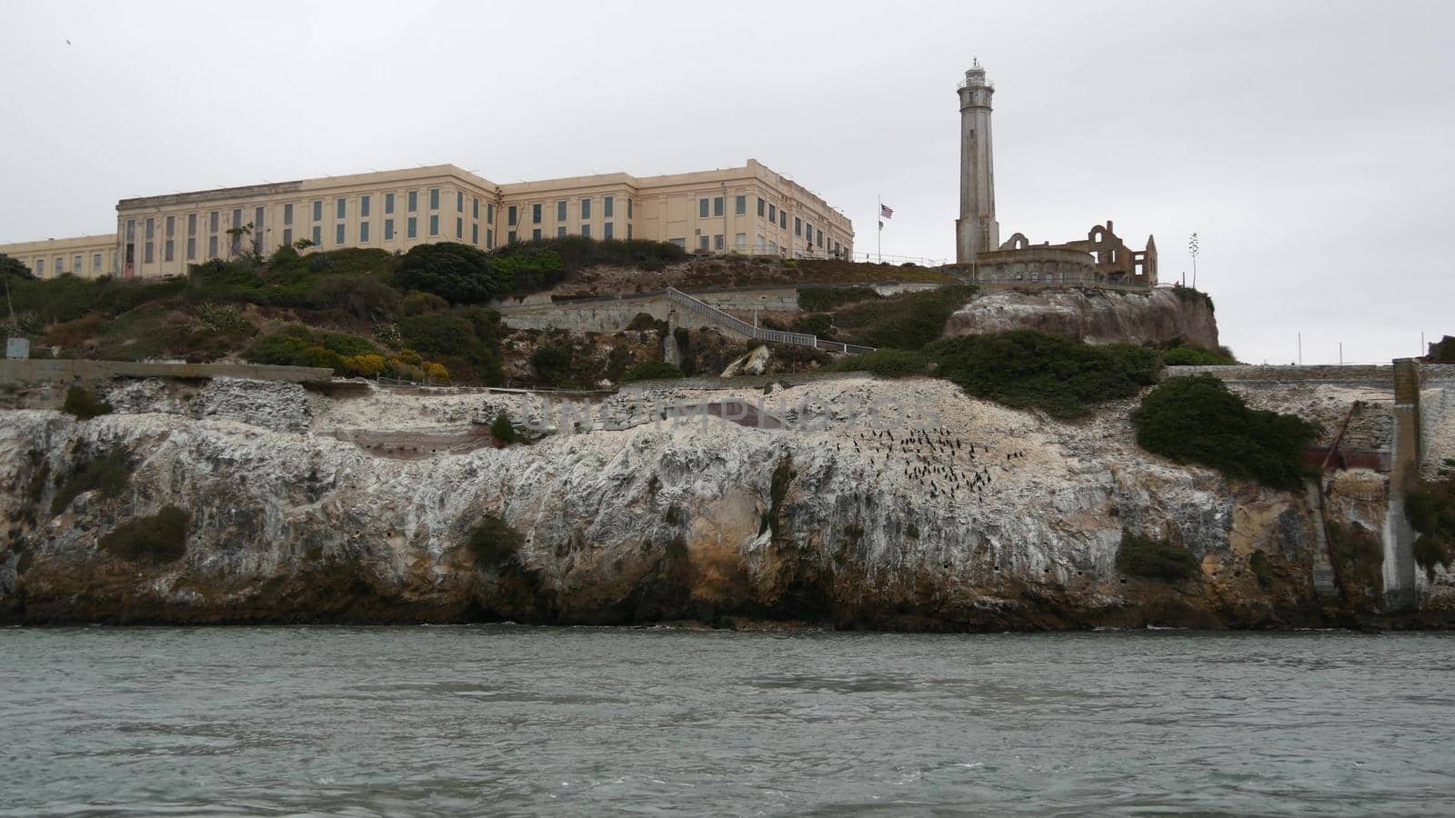 Alcatraz island in San Francisco Bay, California USA. Federal prison for gangsters on rock, foggy weather. Historic jail, cliff in misty cloudy harbor. Gaol for punishment and imprisonment for crime.