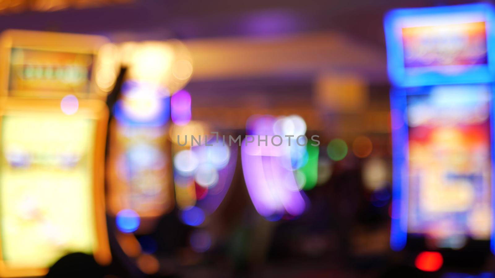 Defocused slot machines glow in casino on fabulous Las Vegas Strip, USA. Blurred gambling jackpot slots in hotel near Fremont street. Illuminated neon fruit machine for risk money playing and betting.