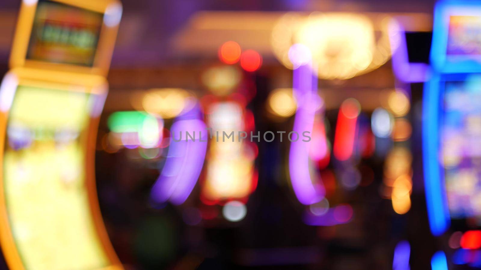 Defocused slot machines glow in casino on fabulous Las Vegas Strip, USA. Blurred gambling jackpot slots in hotel near Fremont street. Illuminated neon fruit machine for risk money playing and betting.