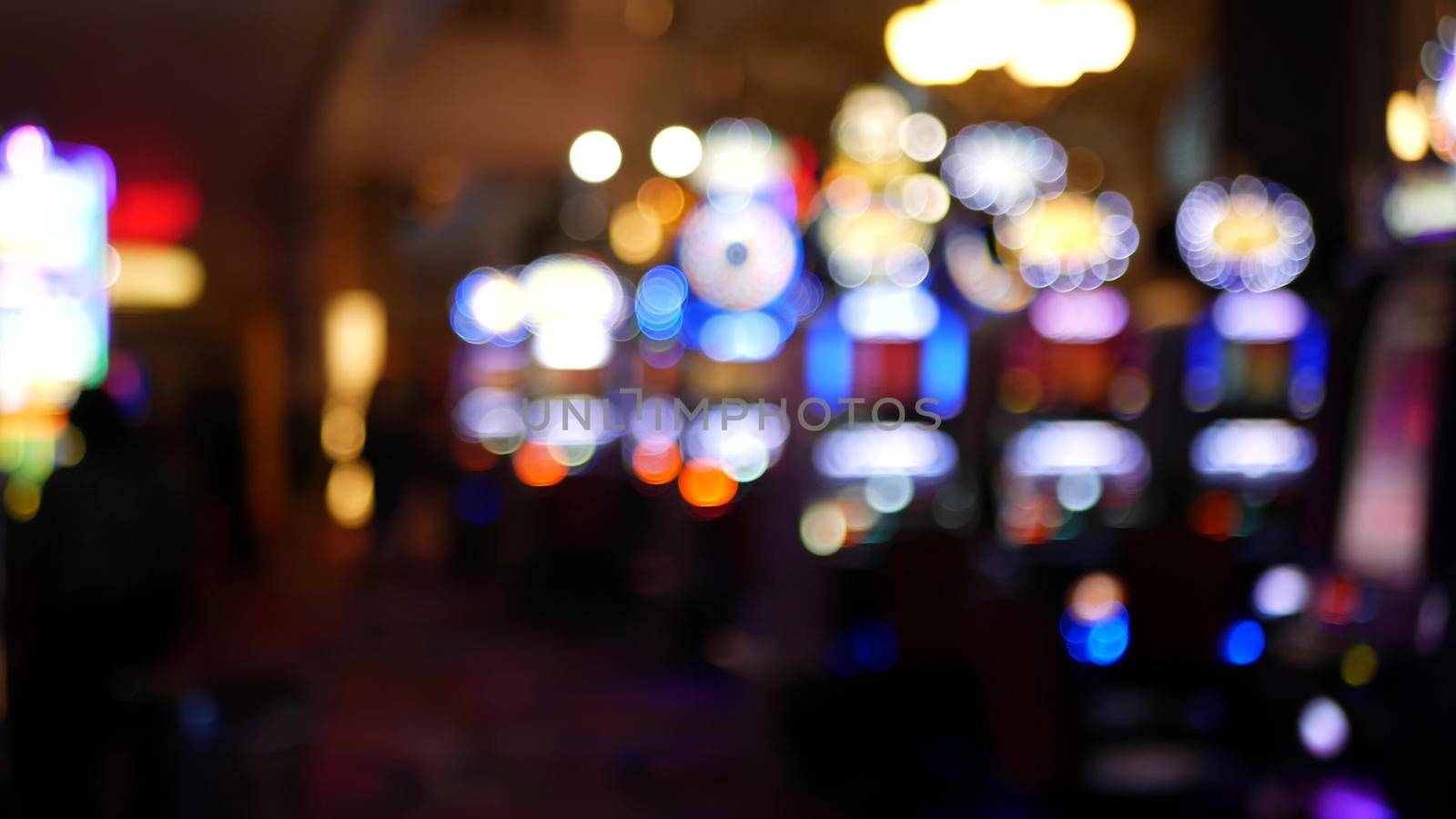 Defocused slot machines glow in casino on fabulous Las Vegas Strip, USA. Blurred gambling jackpot slots in hotel near Fremont street. Illuminated neon fruit machine for risk money playing and betting.