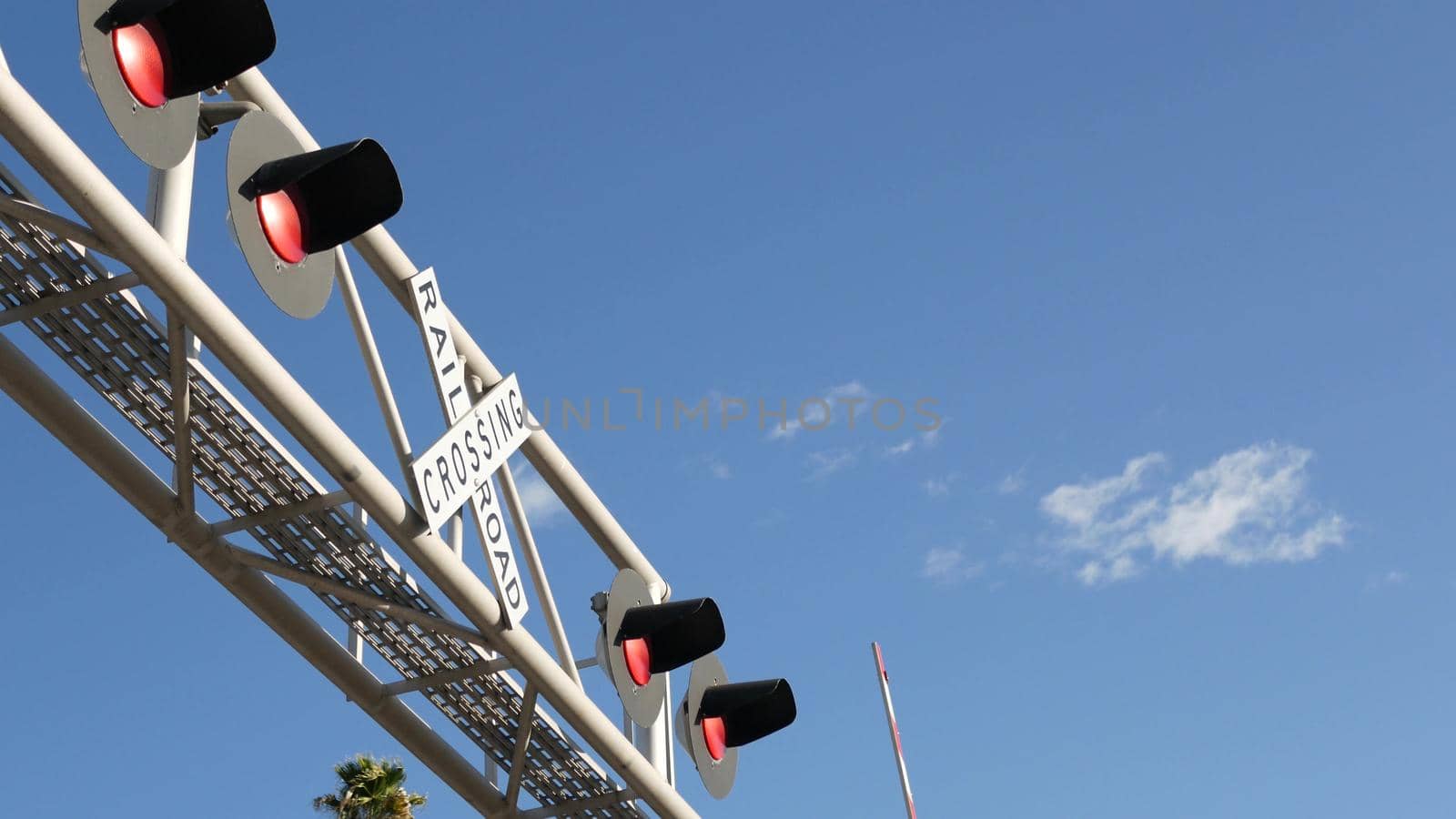 Level crossing warning signal in USA. Crossbuck notice and red traffic light on rail road intersection in California. Railway transportation safety symbol. Caution sign about hazard and train track.