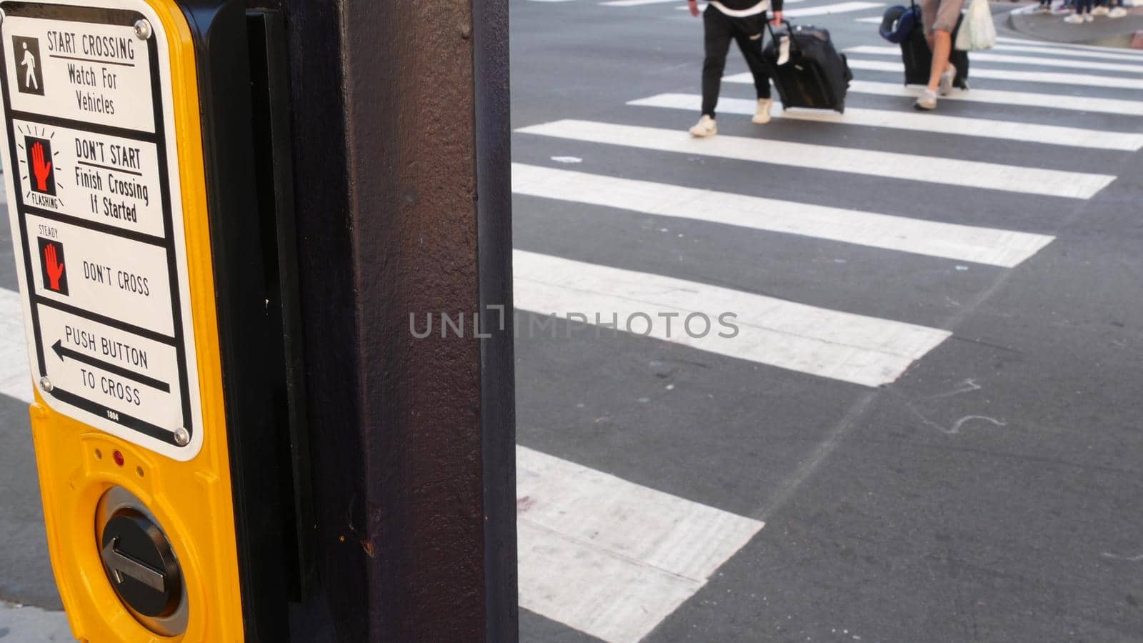 Traffic light button on pedestrian crosswalk, people have to push and wait. Traffic rules and regulations for public safety in USA. Zebra street crossing on road intesection in San Diego, California by DogoraSun