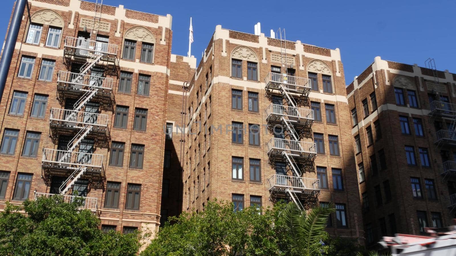 Fire escape ladder outside residential brick building in San Diego city, USA. Typical New York style emergency exit for safe evacuation. Classic retro house exterior as symbol of real estate property.