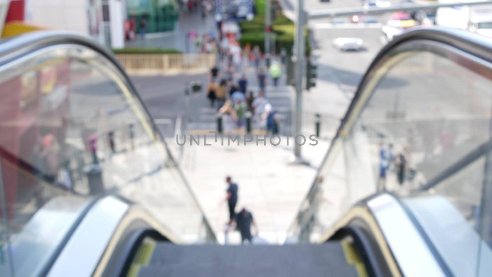 Perspective view thru escalator, defocused unrecognizable group of people on road intersection crosswalk on Strip of Las Vegas, USA. Anonymous blurred pedestrians on walkway in crowded urban downtown by DogoraSun