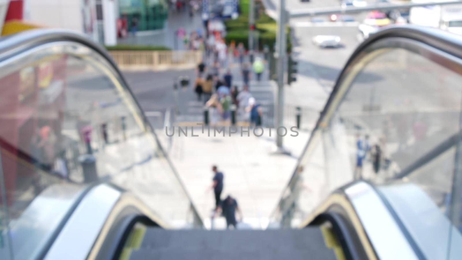 Perspective view thru escalator, defocused unrecognizable group of people on road intersection crosswalk on Strip of Las Vegas, USA. Anonymous blurred pedestrians on walkway in crowded urban downtown.