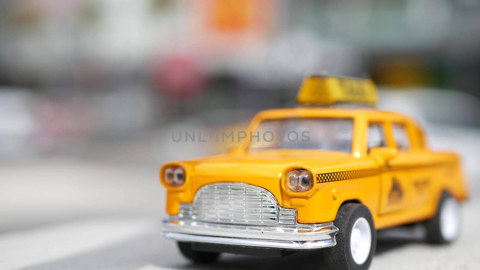 Yellow vacant mini taxi cab close up, Harmon corner, Las Vegas, USA. Small retro car model on defocused background. Little iconic auto toy as symbol of transport in soft focus. Blurred shopping mall.