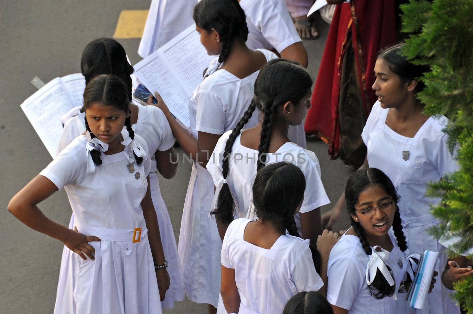 KANDY, SRI LANKA - 14 DECEMBER 2011 Group of young teenage ethnic pupils girls in white school uniform dresses standing outdoors.