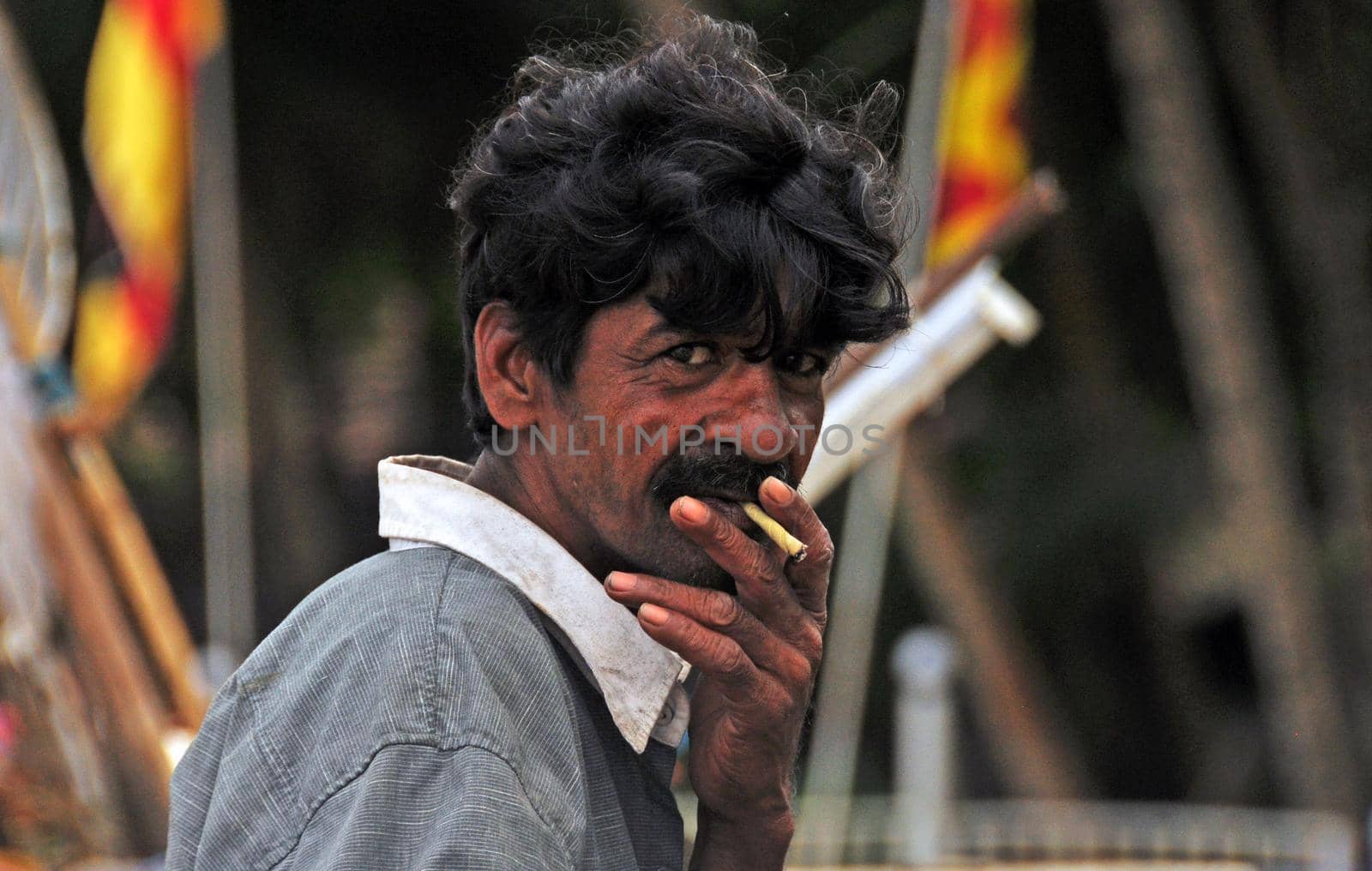 HIKKADUVA, SRI LANKA - 21th DEC, 2011: Indian mature fisherman smoking outdoors, portrait, Mature ethnic man smoking cigarette and looking at camera, Sri Lanka beach