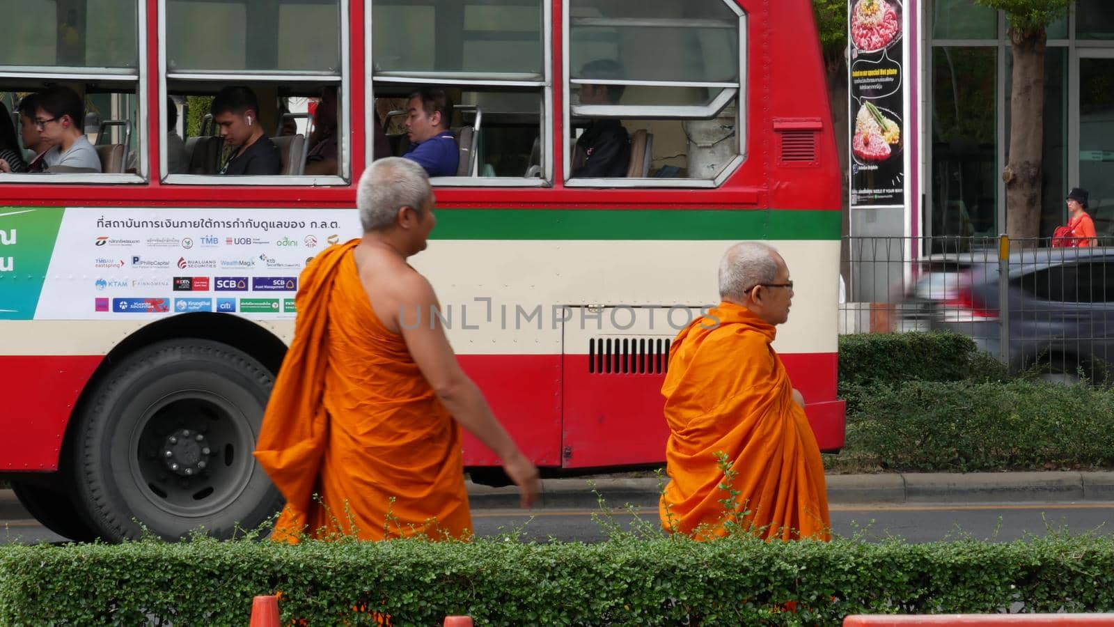 BANGKOK, THAILAND - 13 JULY, 2019: Buddhist holy Monk in traditional orange robe on the steet. Monks yellow religious clothes among people near the road looking for taxi transport. Urban city life