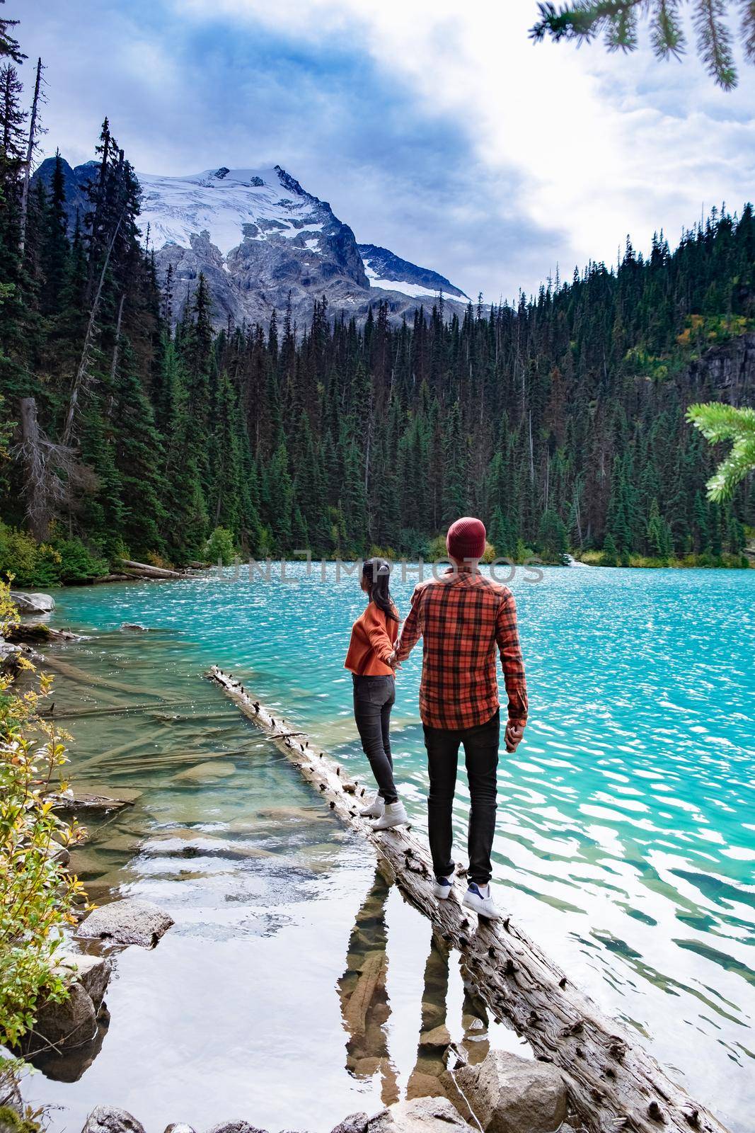 Majestic mountain lake in Canada. Upper Joffre Lake Trail View, couple visit Joffre Lakes Provincial Park - Middle Lake. British Columbia Canada, couple men and woman hiking by the lake