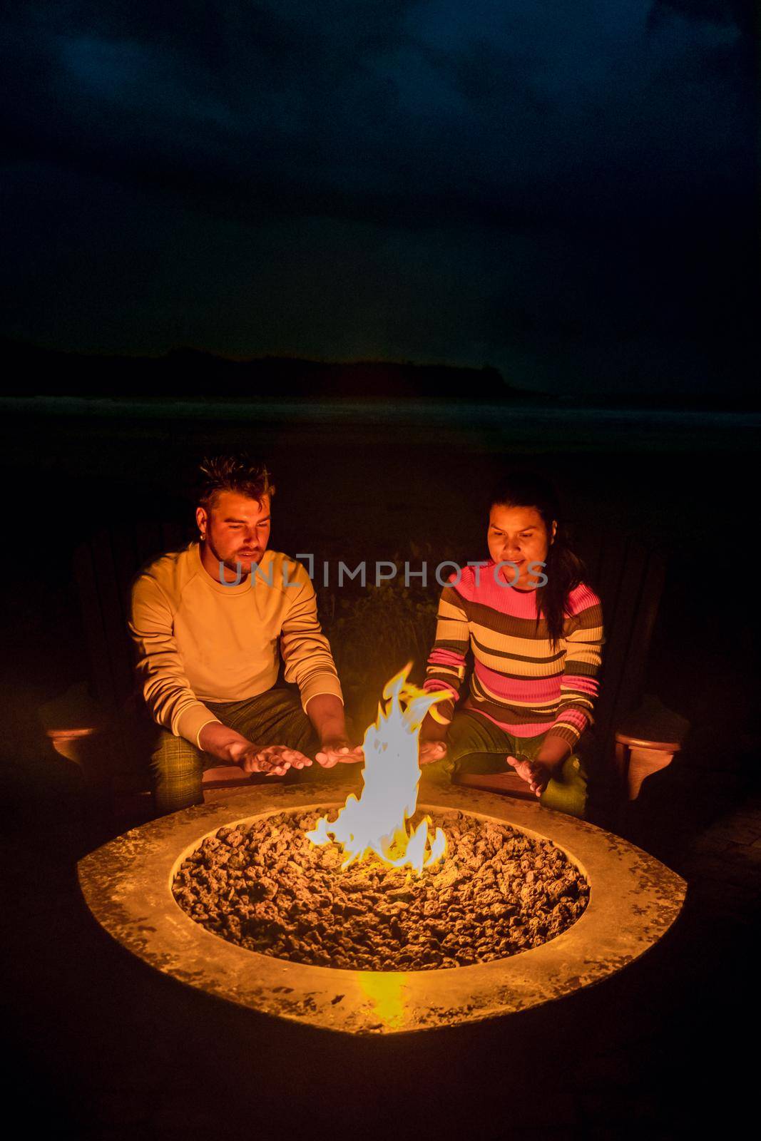 couple mid age men and woman by campfire on the beach at night at Vancouver Island Canada. men and woman by fireplace at the beach