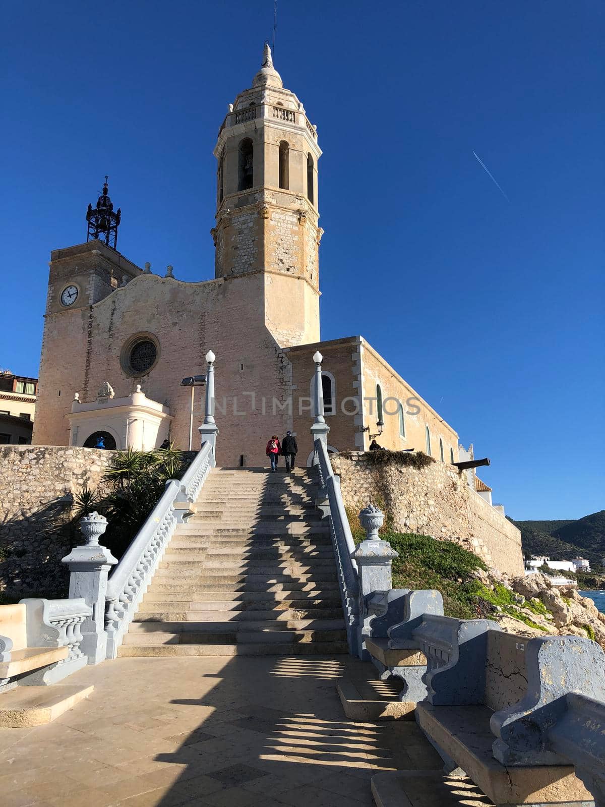 Couple walking towards the Church of Sant Bartomeu & Santa Tecla in Sitges, Spain