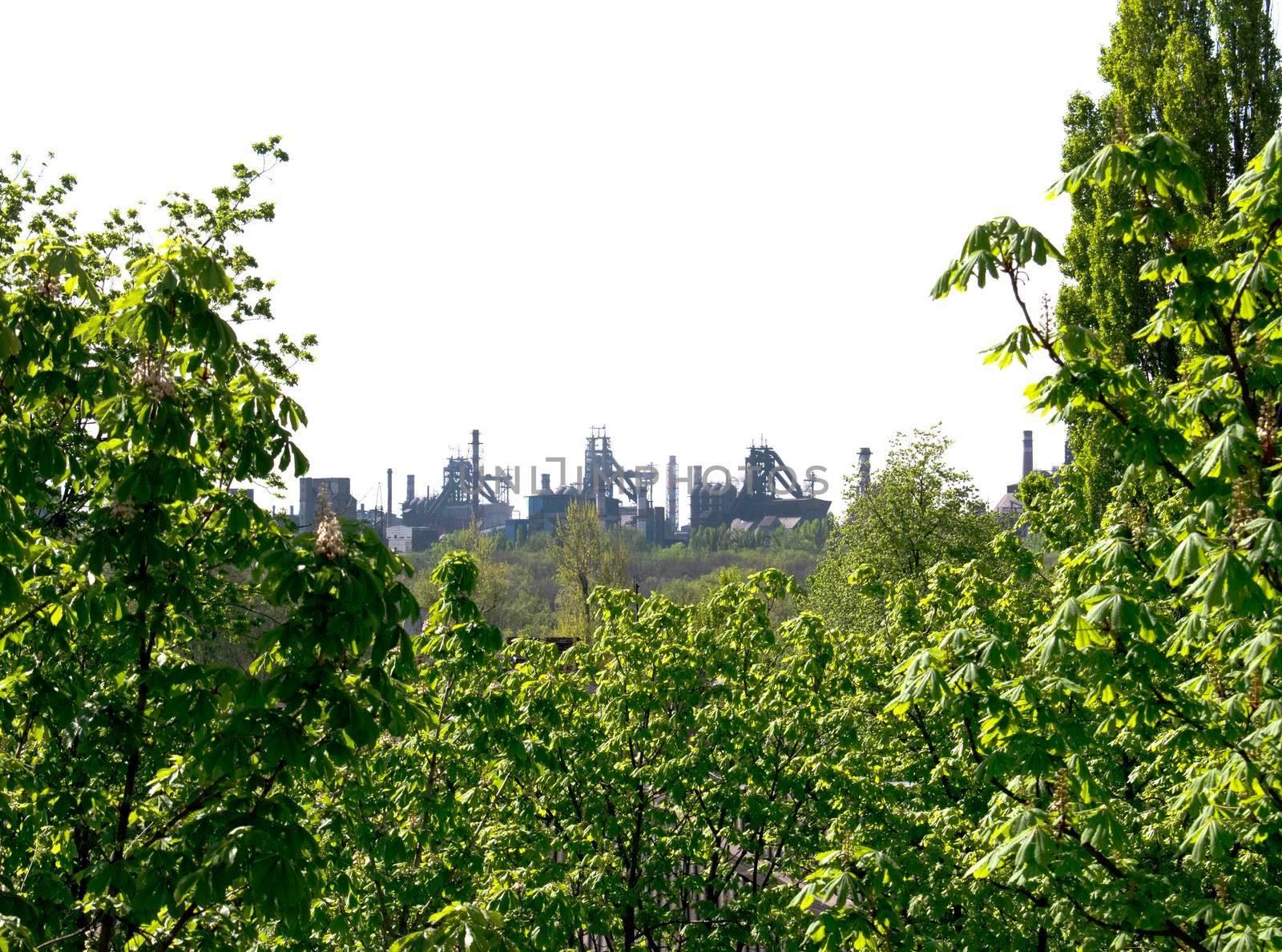 Metallurgy plant against the background of blooming green chestnuts.