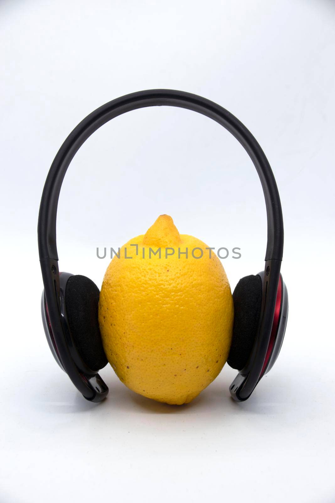 Yellow lemon in headphones on a white background.