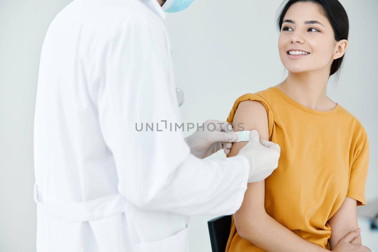 doctor in protective gloves tapes the shoulder of a woman by SHOTPRIME