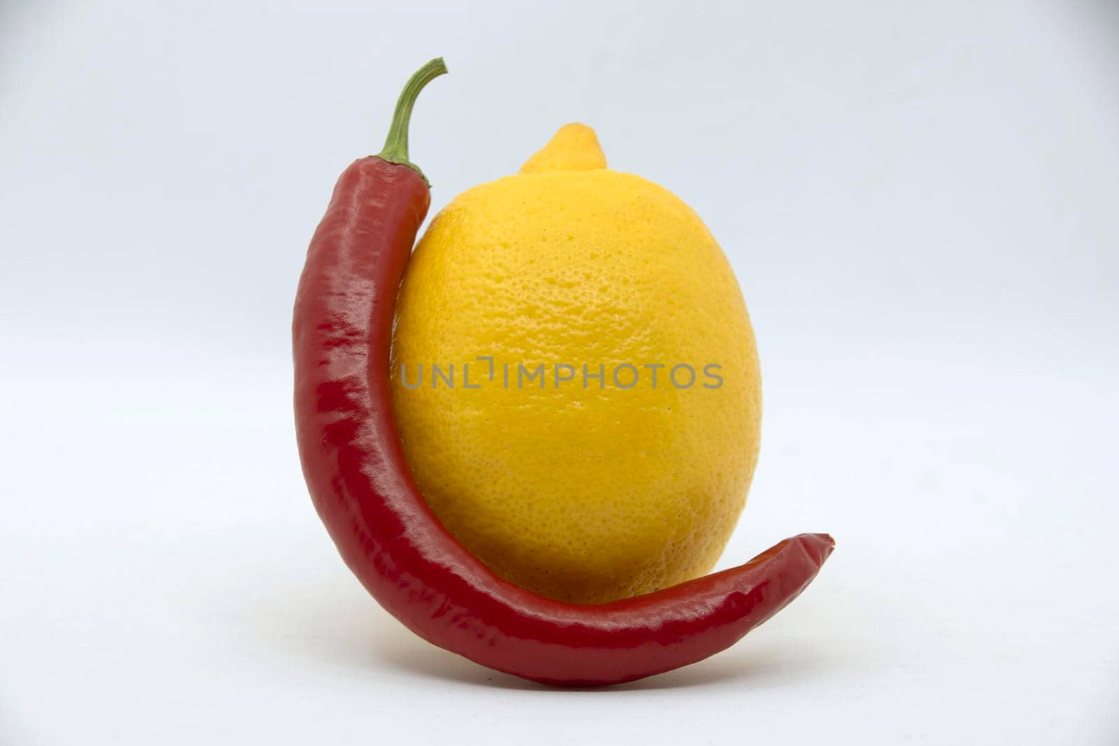 Yellow lemon with bitter red pepper on a white background.