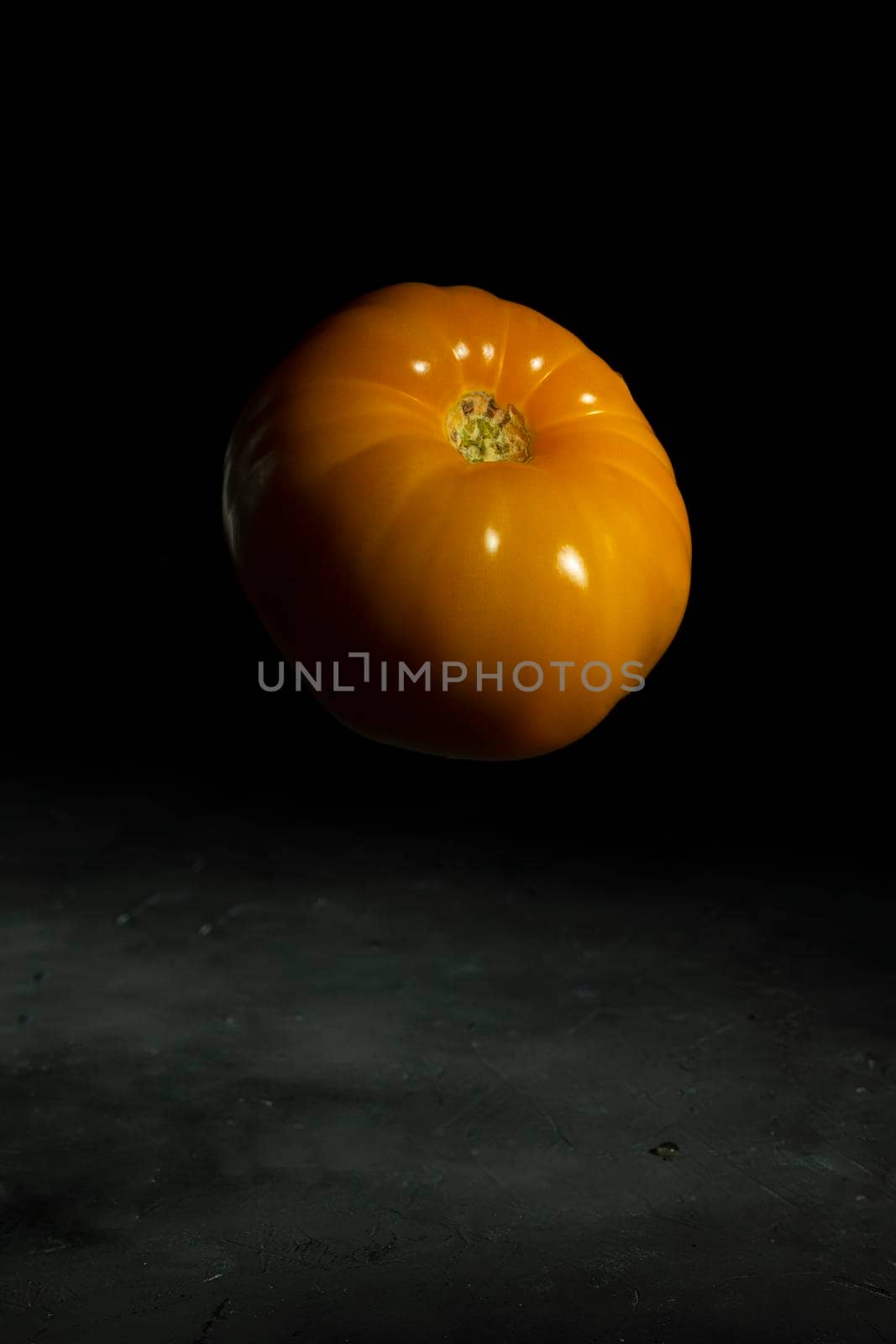Fresh yellow tomato on the black background by sashokddt