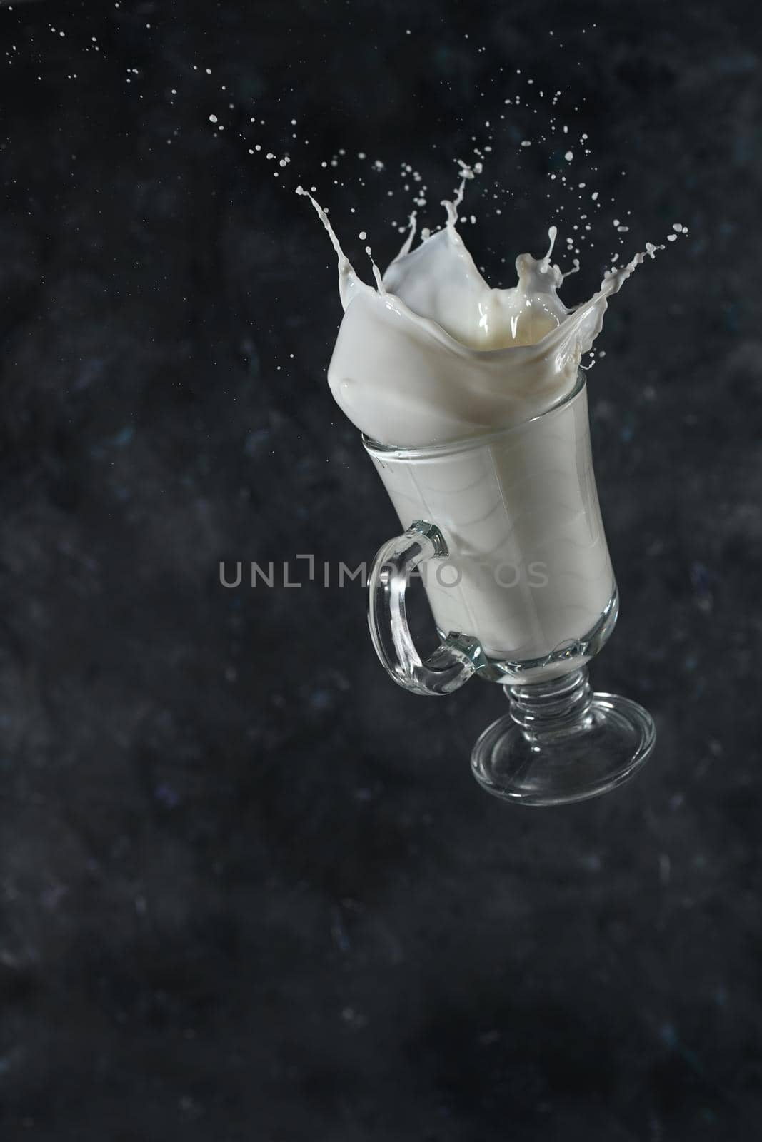 Splash of milk from the glass on a gray background. levitation by sashokddt