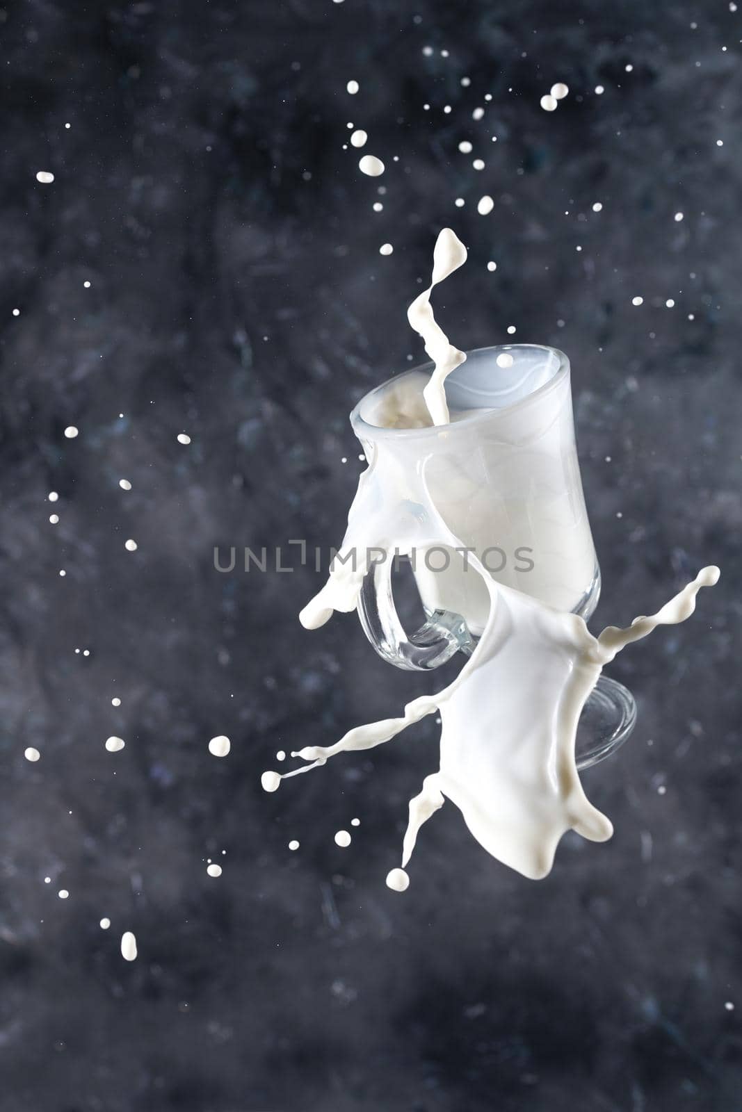 Splash of milk from the glass on a gray background. levitation by sashokddt