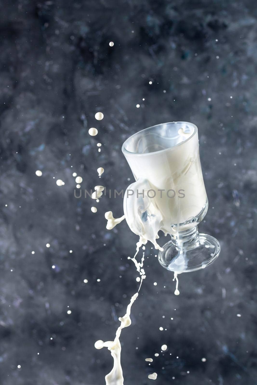 Splash of milk from the glass on a gray background. levitation.
