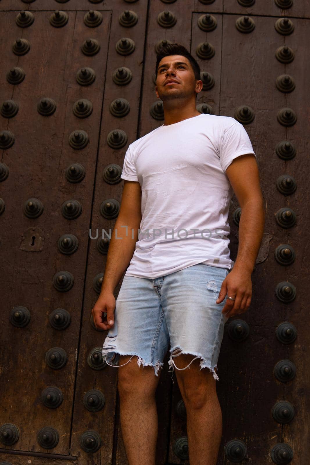 Man with a white T-shirt and a brown door in the background modeling