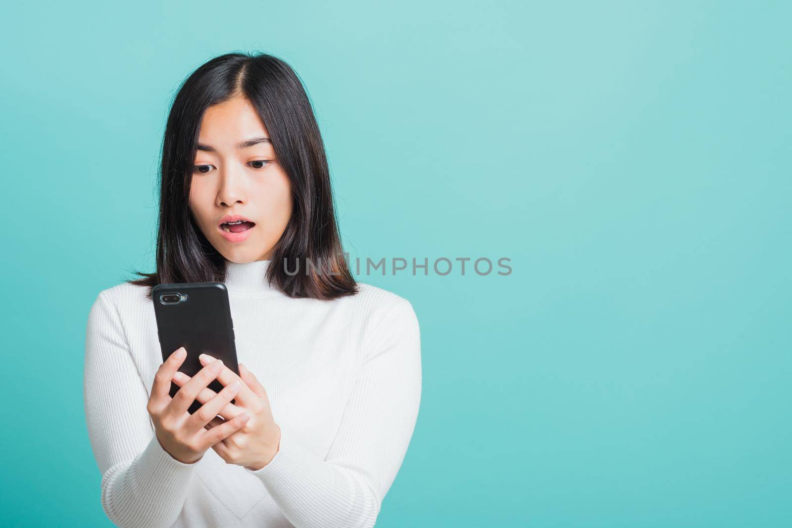 woman surprised shocked with mobile phone close mouth with palm by Sorapop