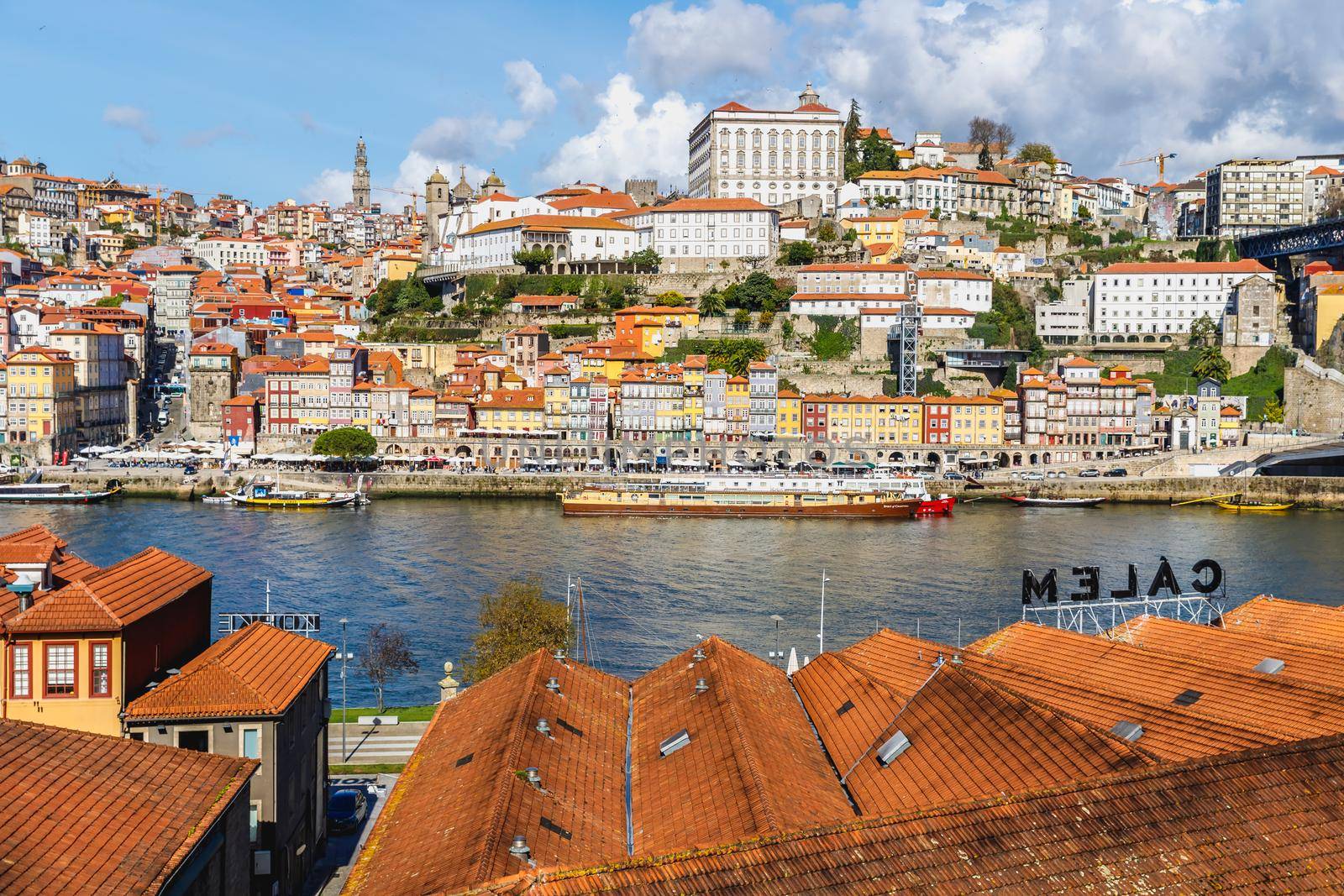 Porto, Portugal - October 23, 2020: View of the buildings with typical architecture and boats of tourist areas on the banks of the Douro river on an autumn day