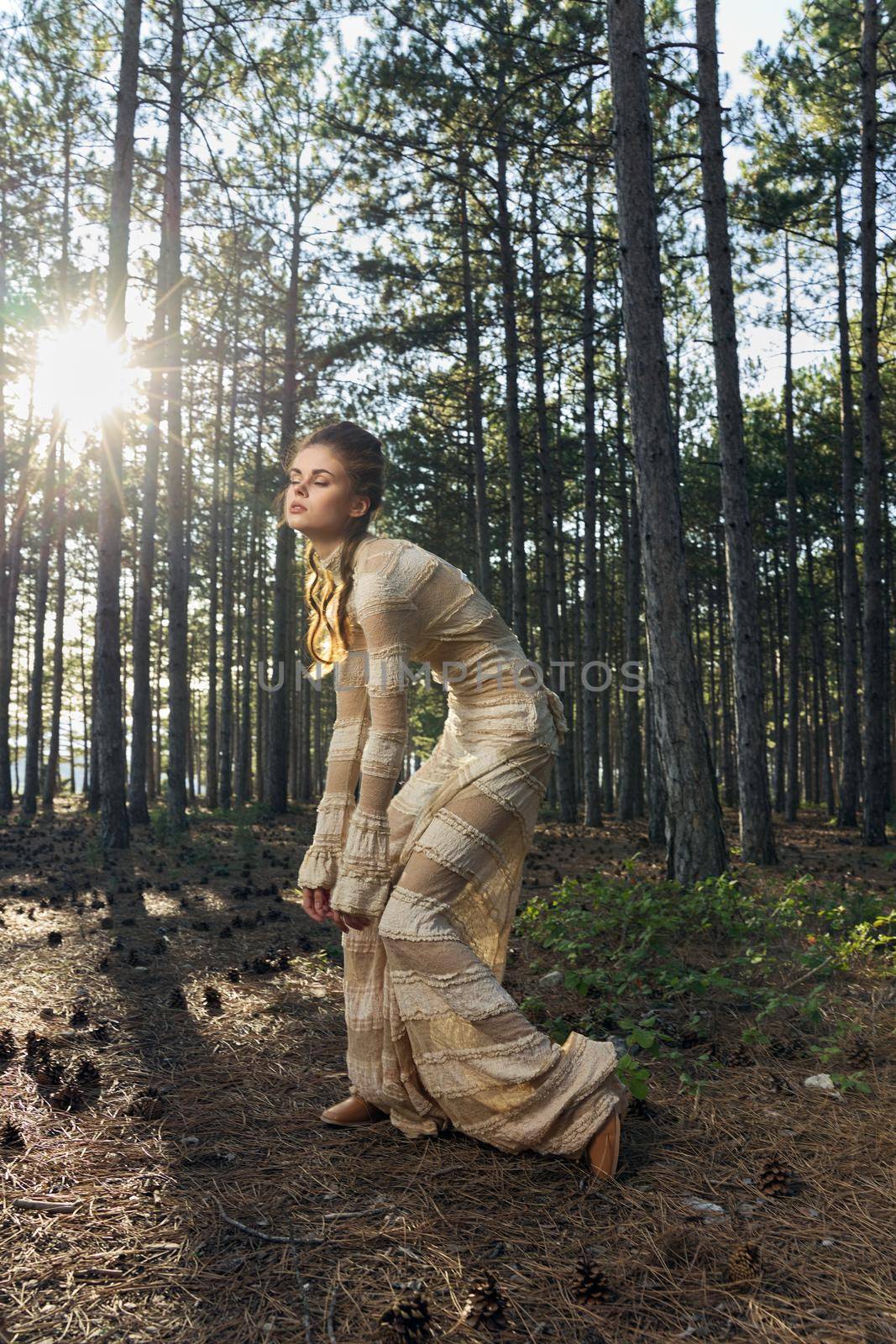 A woman in a dress is dancing barefoot in a coniferous forest in nature in the park. High quality photo