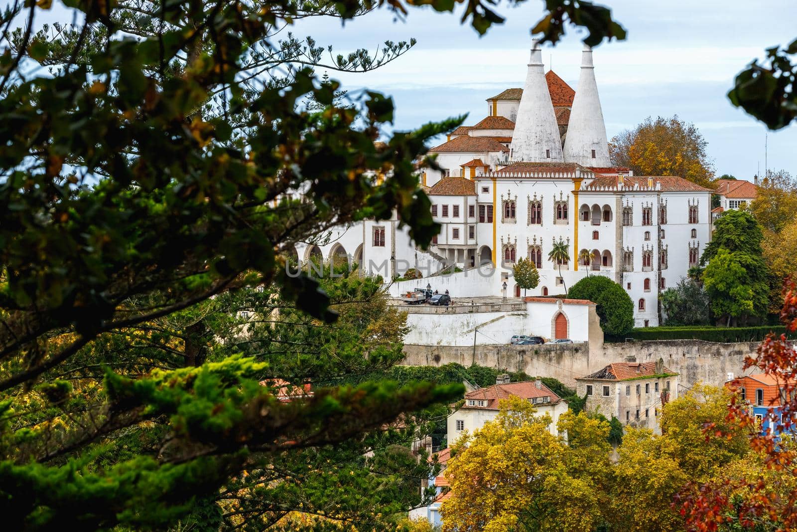 Sintra, Portugal - October 28, 2020: Architectural detail of the National Palace of Sintra, also called the Royal Palace with its 2 chimneys of 33 meters behind trees on a winter day