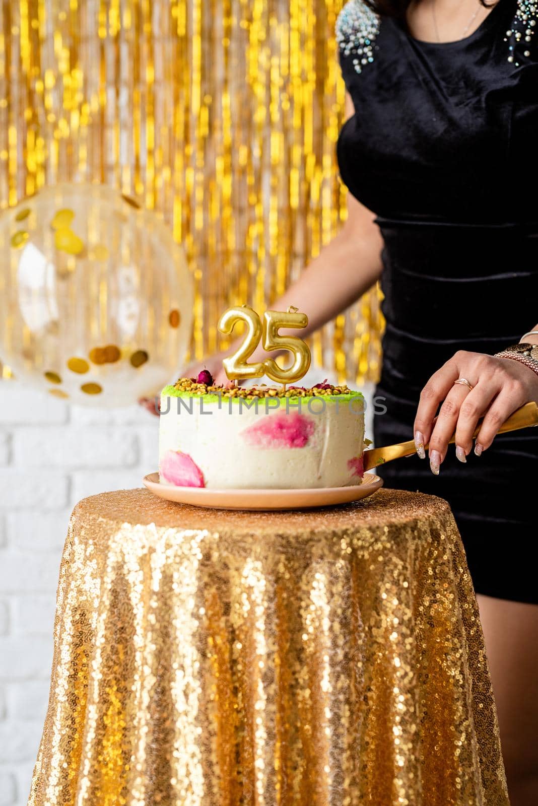 Birthday party. Beautiful brunette woman in black party dress holding ballooncelebrating her birthday cutting the cake