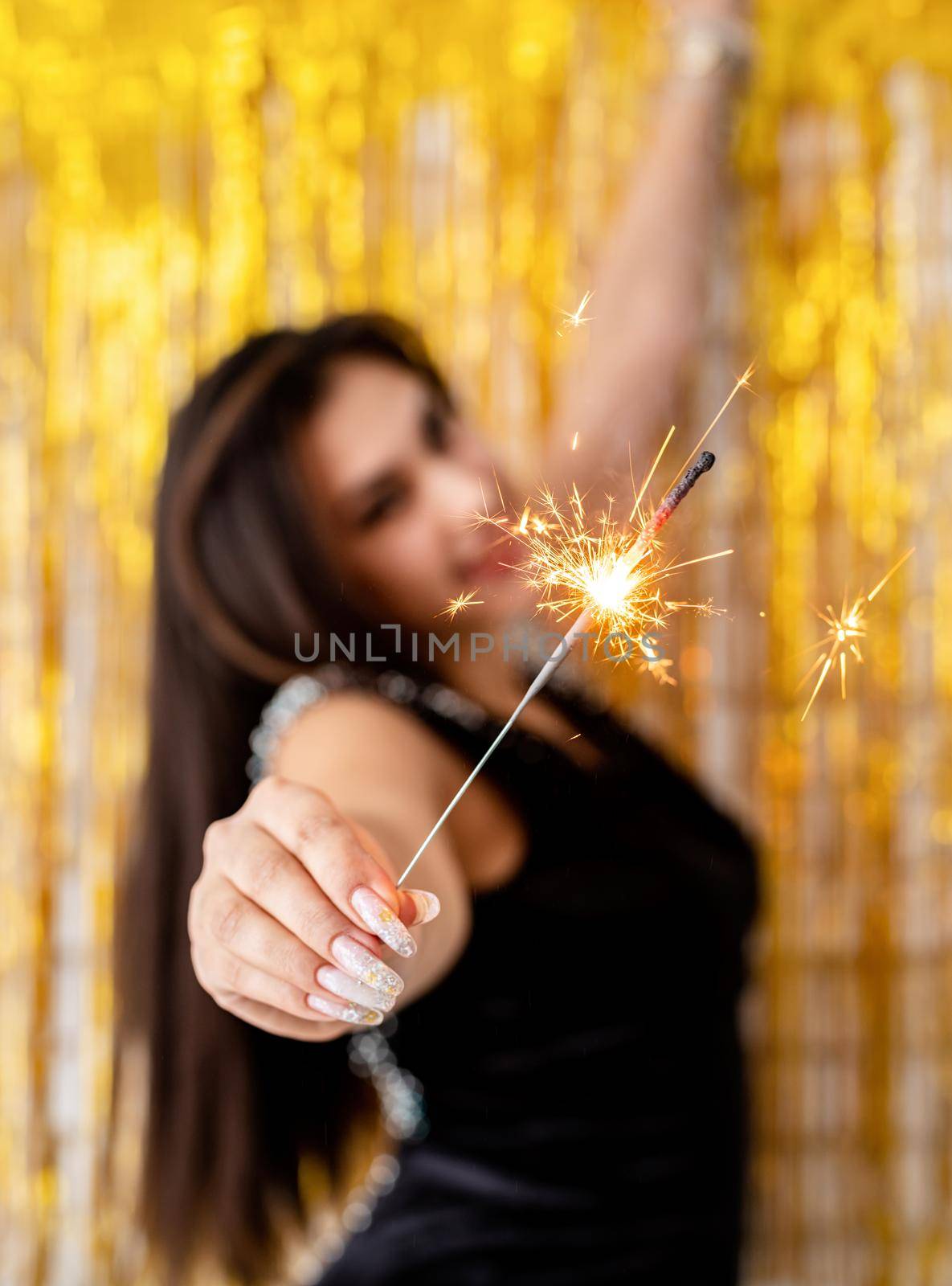 Beautiful young woman holding sparkler and balloon on golden background by Desperada