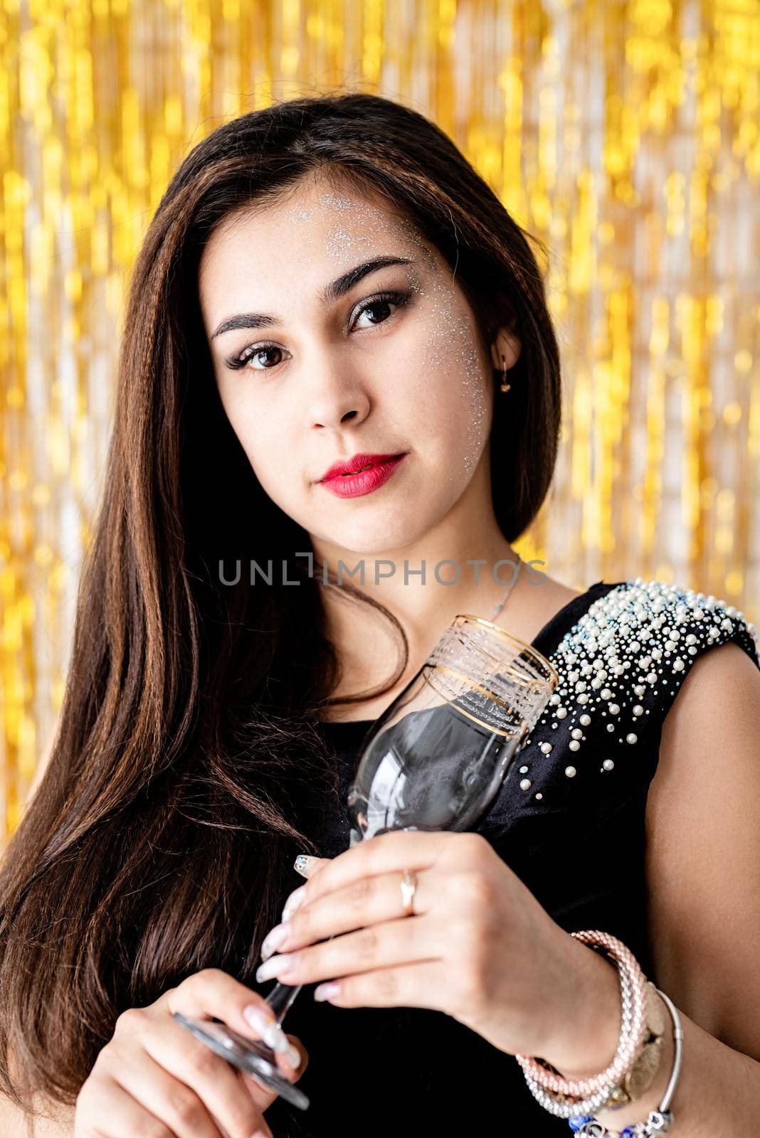 Beautiful brunette woman in black party dress celebrating her birthday holding champagne flute by Desperada