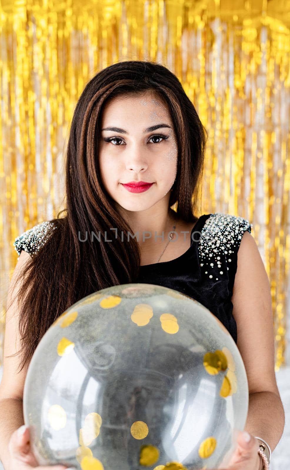 Birthday party. Beautiful smiling brunette woman in black party dress celebrating her birthday holding balloon