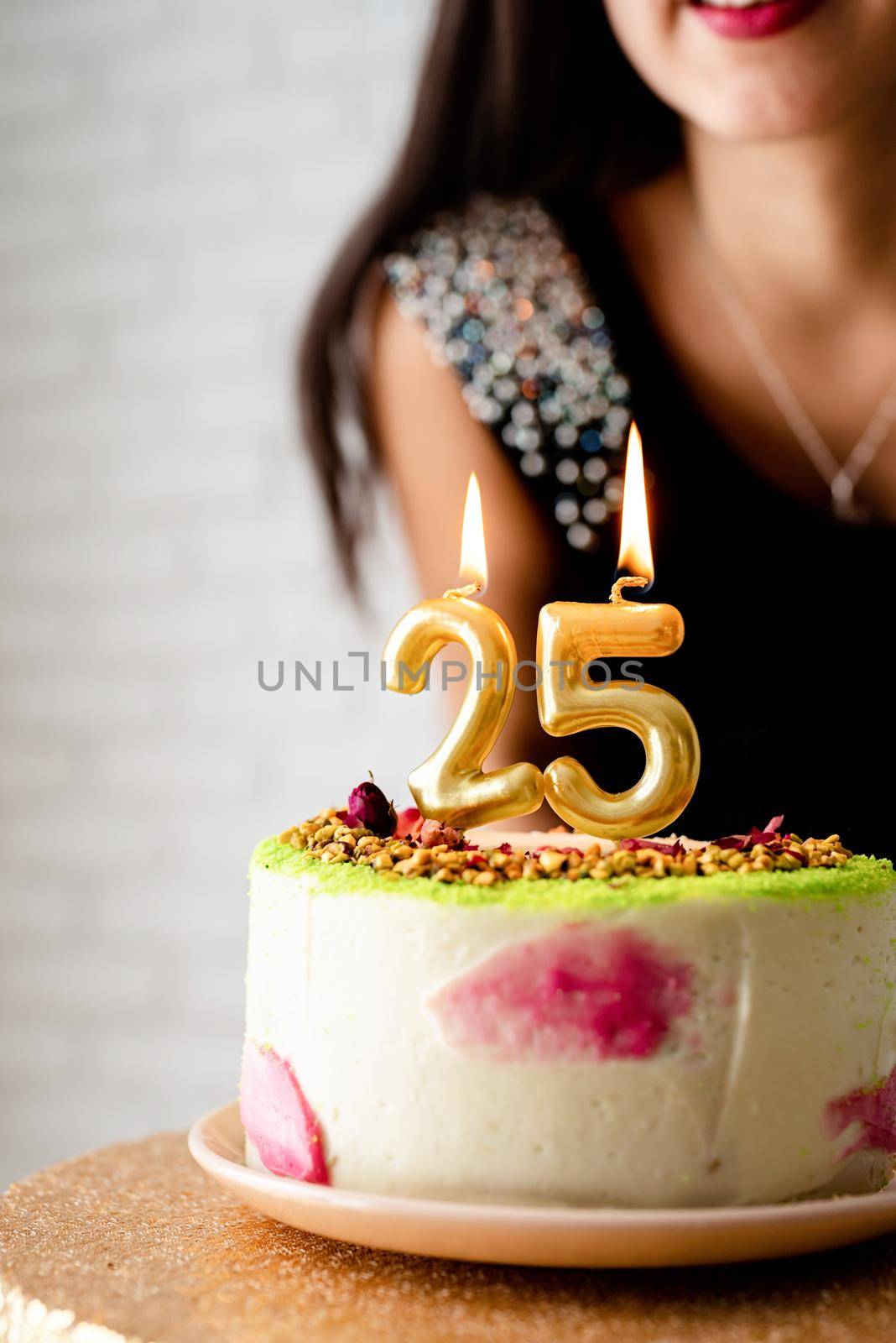 caucasian woman in black party dress lighting candles on birthday cake by Desperada