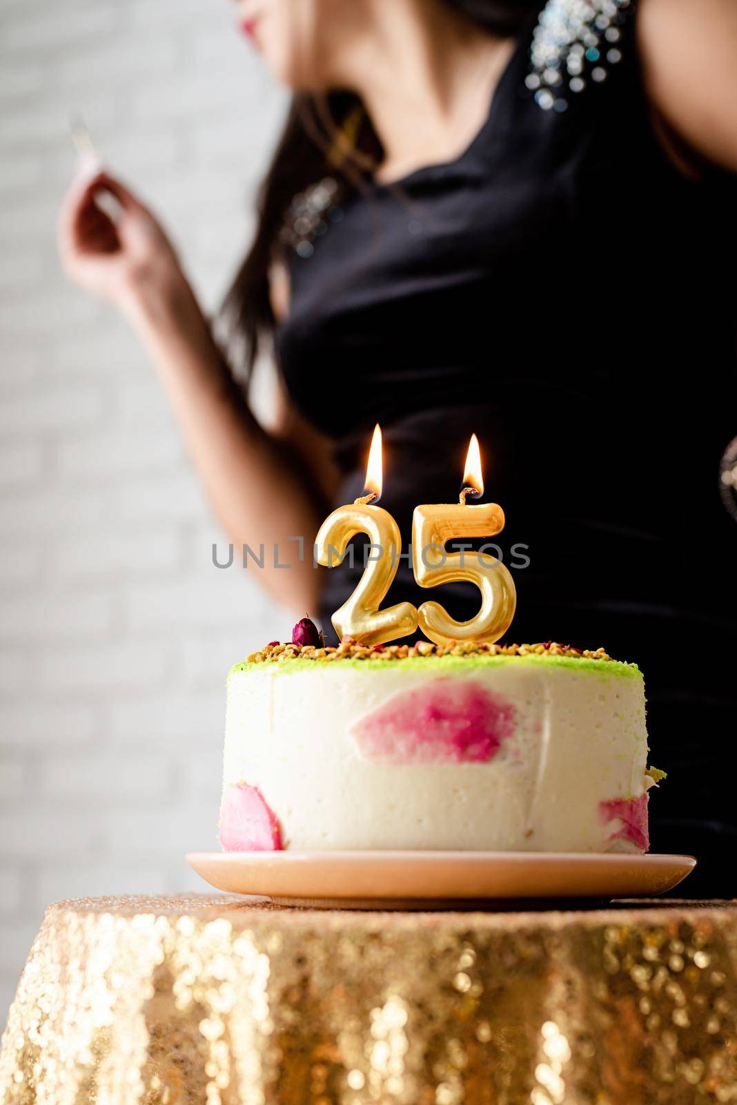 Birthday party. Caucasian woman in black party dress lighting candles on birthday cake