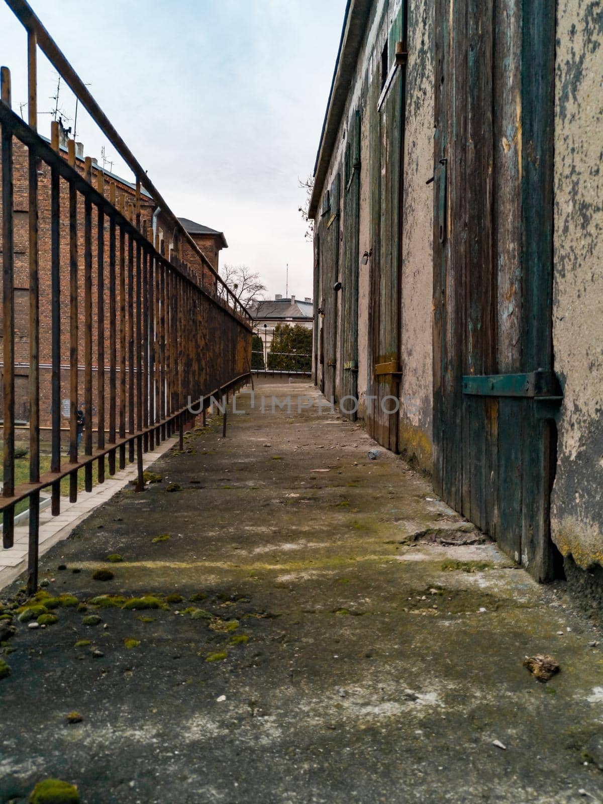 Long concrete balcony between metal railing and old wooden doors