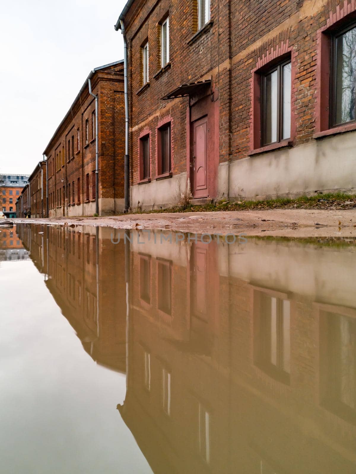 Row of old red brick tenement houses reflected in puddle