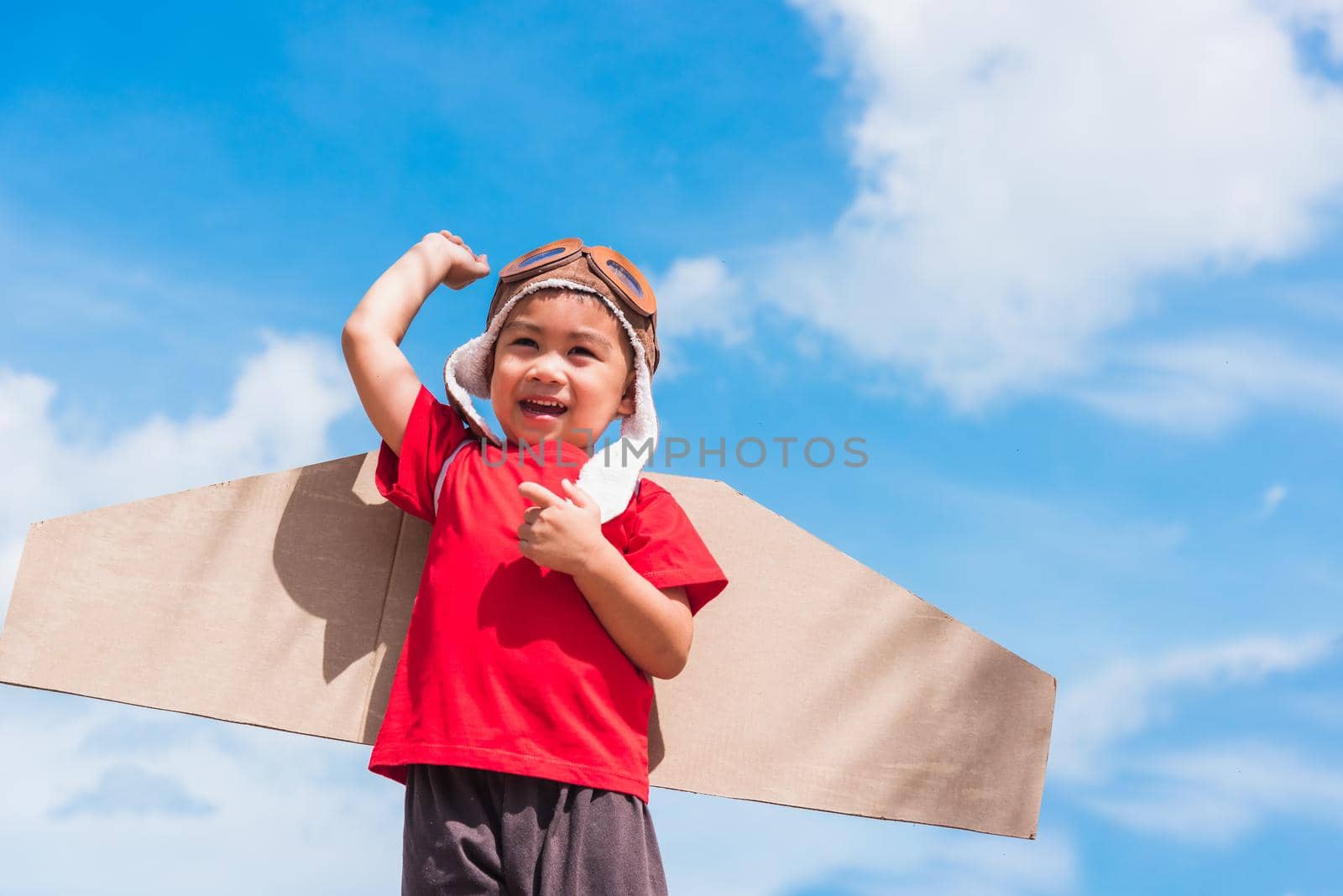 Kid little boy smile wear pilot hat play with toy airplane wing flying by Sorapop