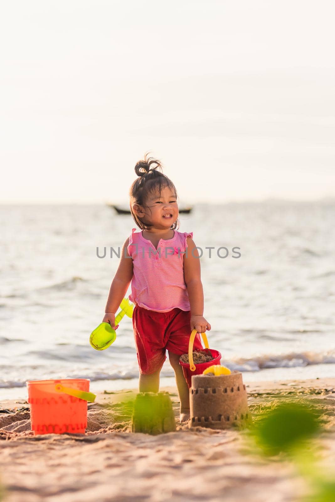 little girl playing sand with toy sand tools by Sorapop