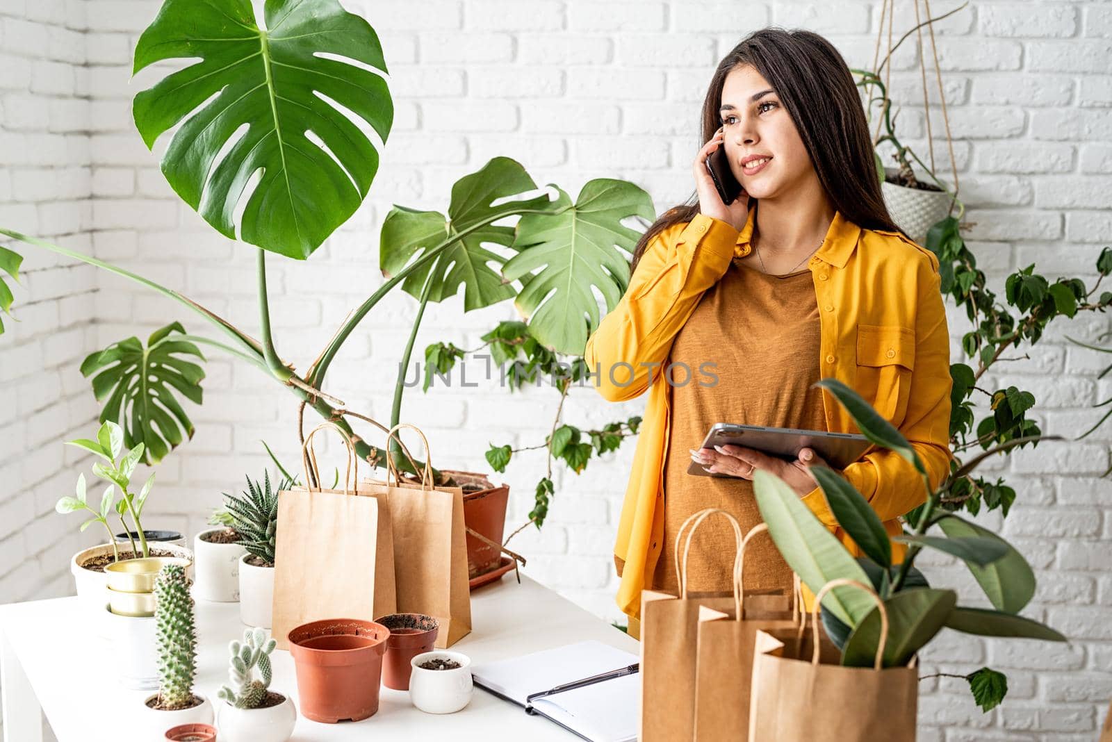 Woman gardener working on digital tablet and making a call by Desperada