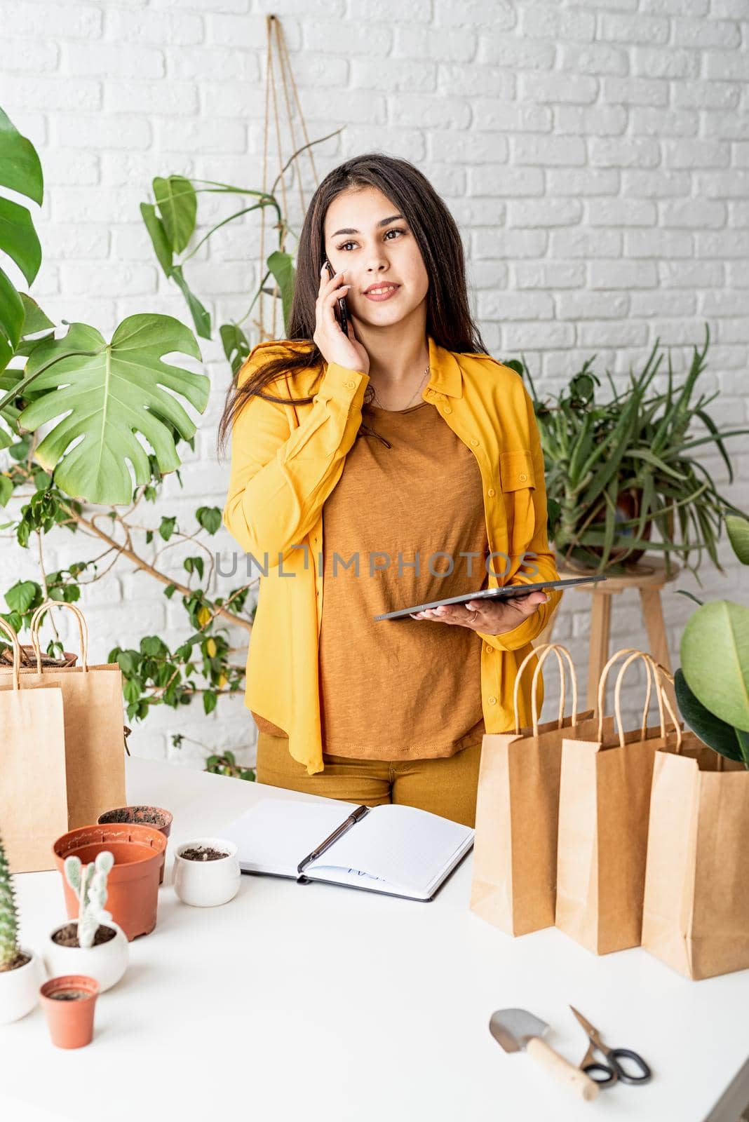 Woman gardener working on digital tablet and making a call by Desperada