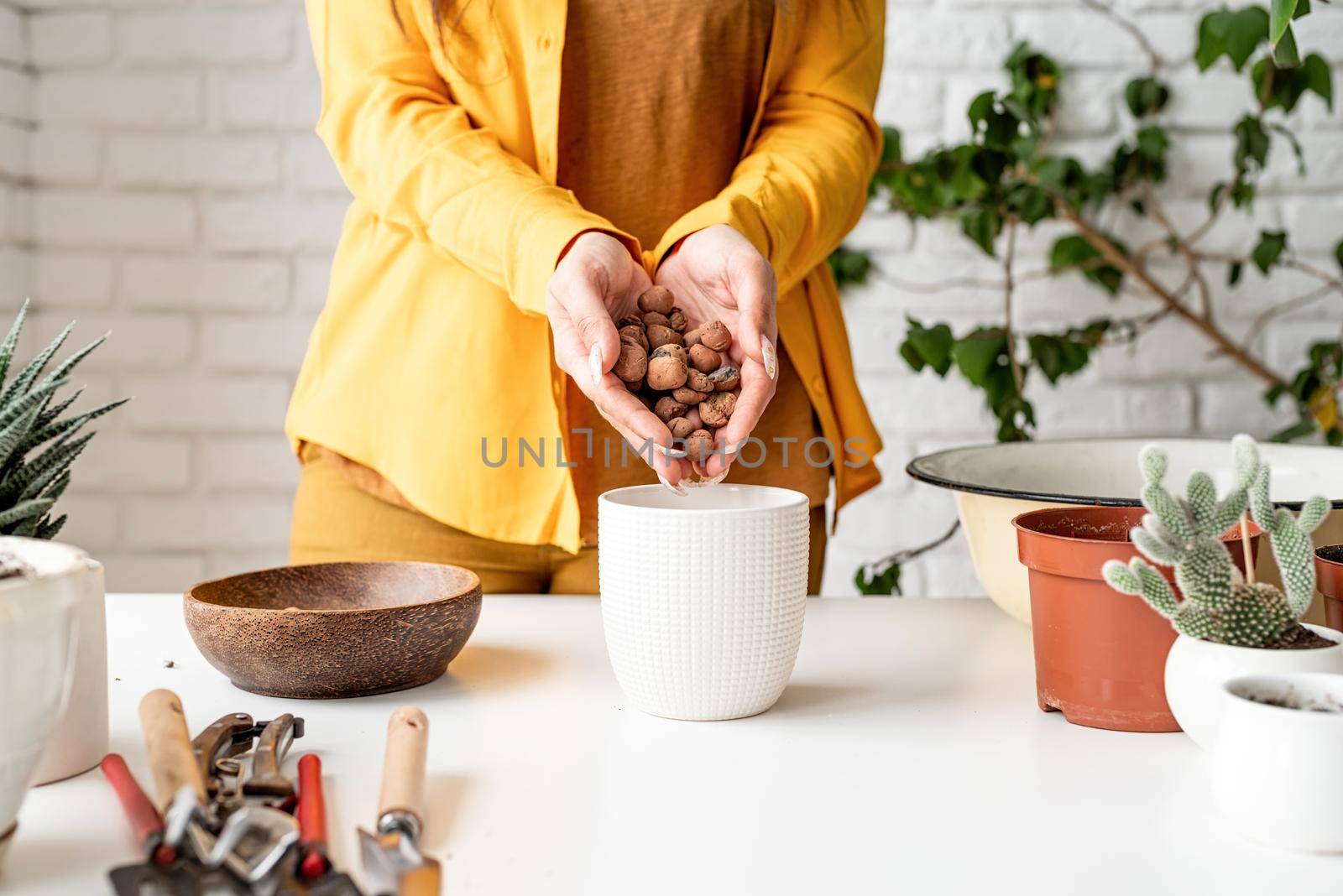 Home gardening. Woman gardener hands putting draining and soil into a new flowerpot