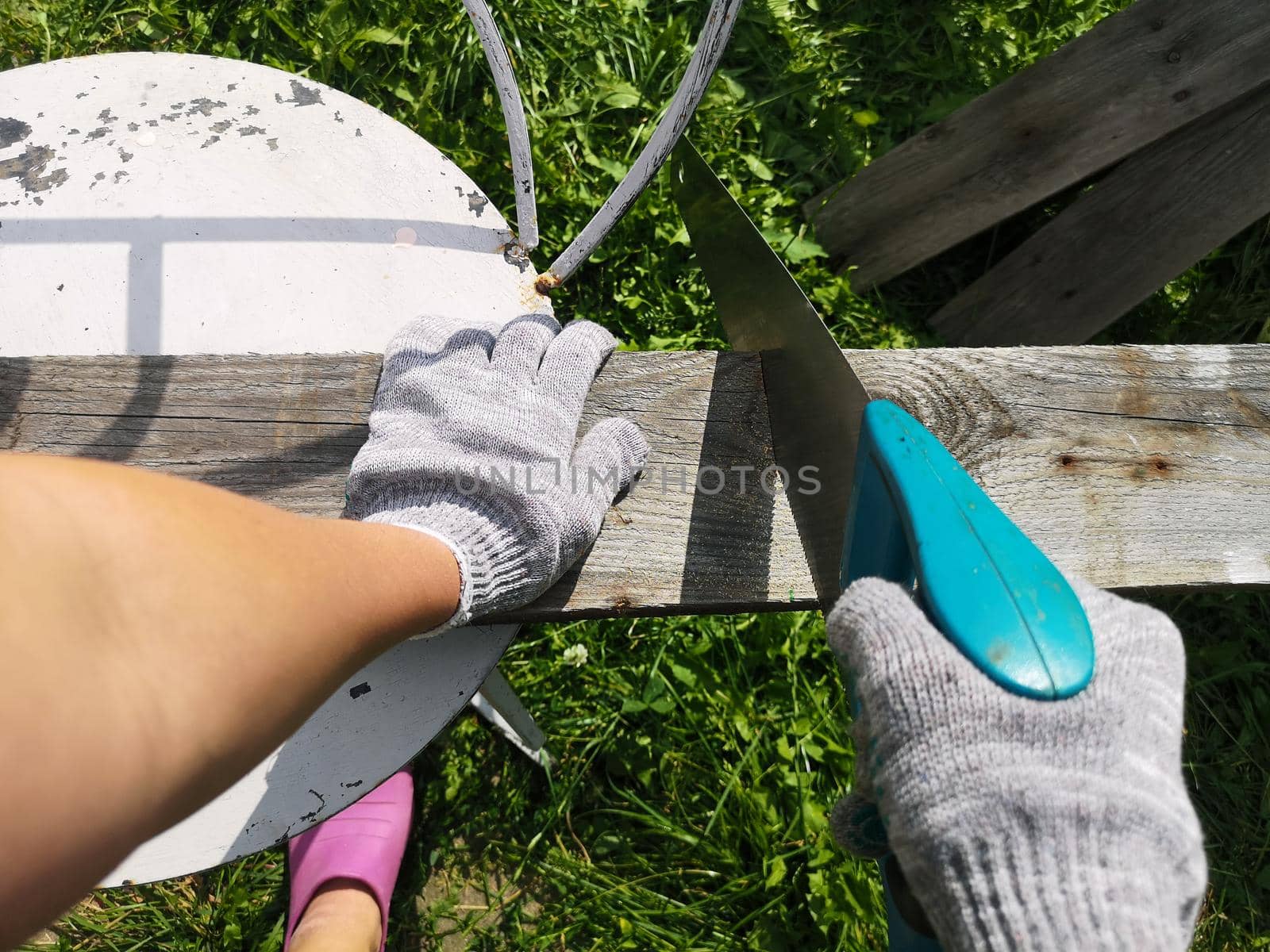 Farmer hand with saw cutting wooden boards in the garden by galinasharapova