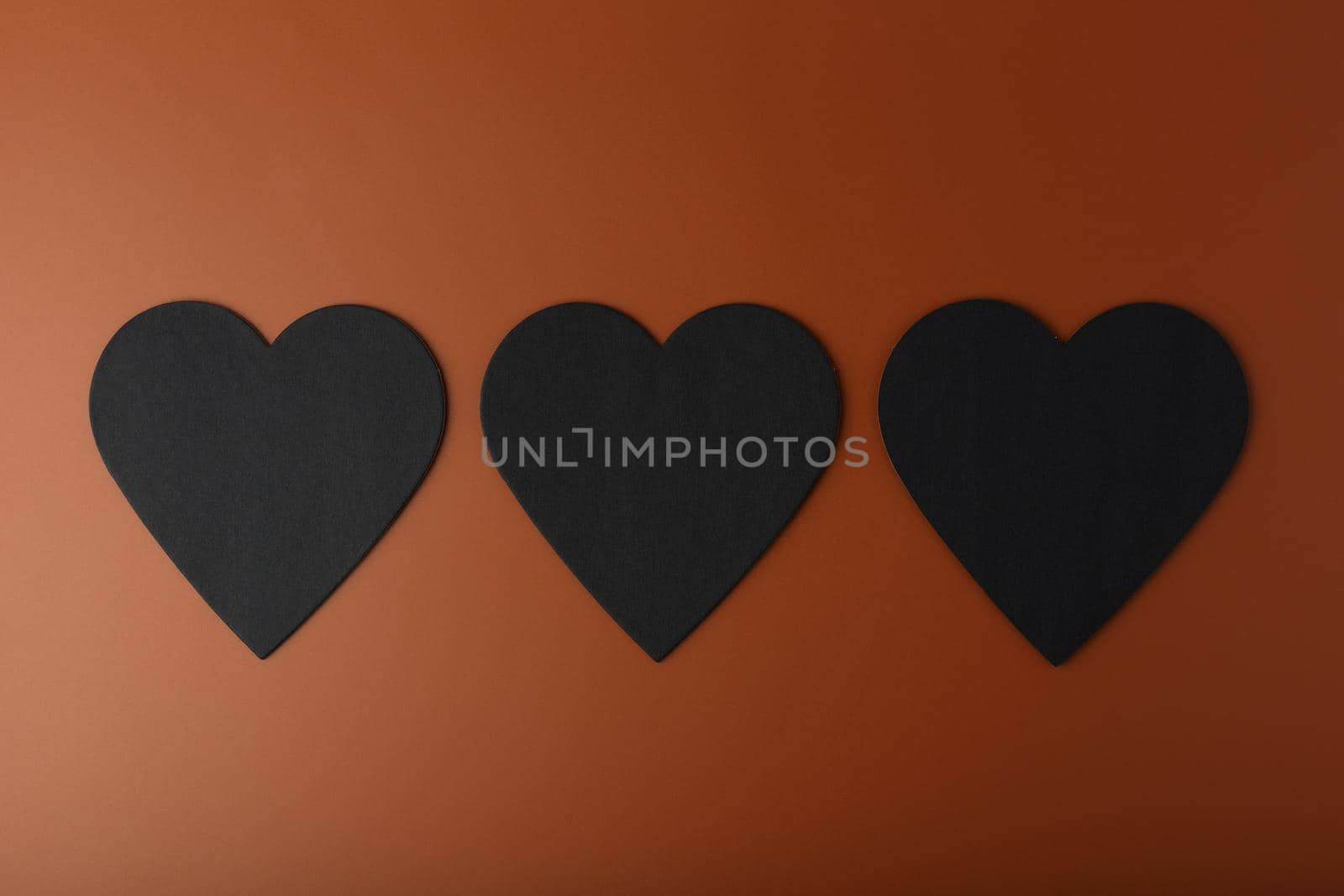 Flat lay with three black hearts on brown background. Concept of love and relationship by Senorina_Irina