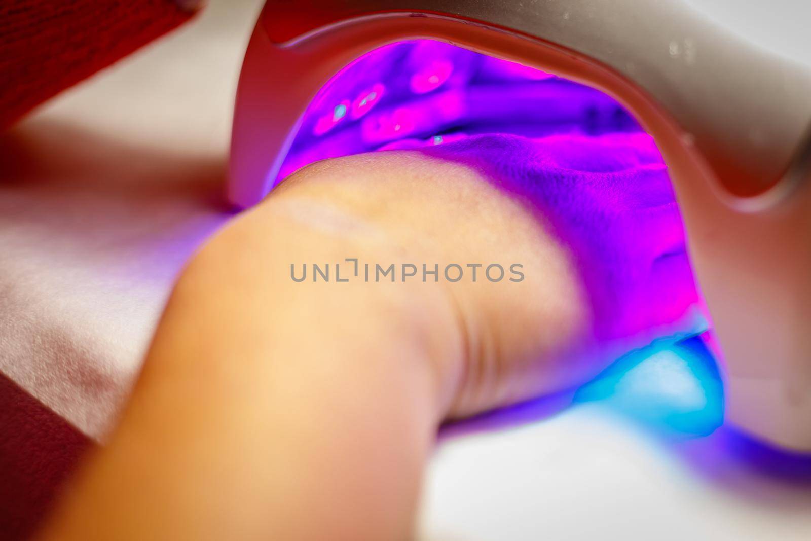 Woman's hand in a lamp for manicure. Dries nails after polishing. UV LED lamp.