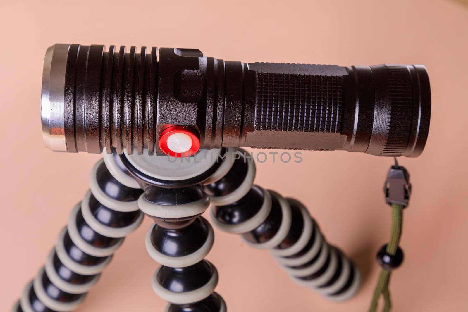 The light for the photographer is durable, powerful, made of aluminum. Flashlight on a pink background